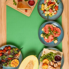 Holiday celebration table setting with food. Flat-lay of sweet cheesecake, fruit salad, meat dishes. Copy space banner.