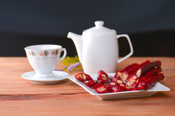 Tasty oriental sweets. Caucasian delicacy churchkhela - georgian nut treats. Served with a glass of tea and a tea pot.