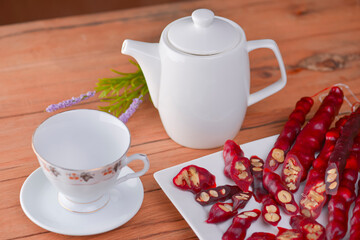Tasty oriental sweets. Caucasian delicacy churchkhela - georgian nut treats. Served with a glass of tea and a tea pot.
