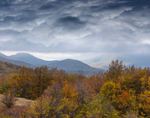 mountain valley with autumn forest under a dense dramatic clouds