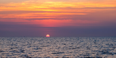 Sunset over the ocean Peaceful seascape. Beautiful cloudy sky over calm sea with sunlight reflection. Copy space banner.