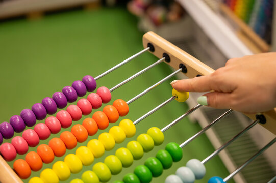 Closeup female hand calculating with balls on wooden rainbow abacus for number calculation. The concept of learning arithmetic for preschoolers.