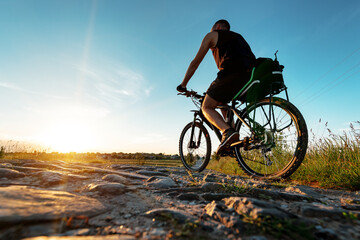 Naklejka na ściany i meble back view of a man with a bicycle against the blue sky. cyclist rides a bicycle.