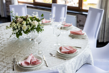 Festive table setting with wine glasses, and fresh white rose