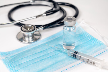 Medical concept with syringe and ampoule over a disposable mask.