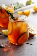 Traditional iced tea with lemon, lime and ice garnished with rosemary twigs.