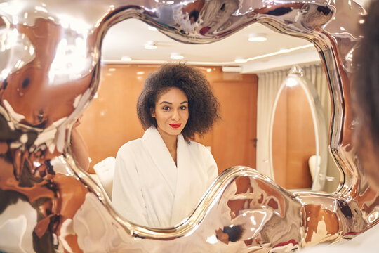Gorgeous refrection of positive curly lady in spa parlor