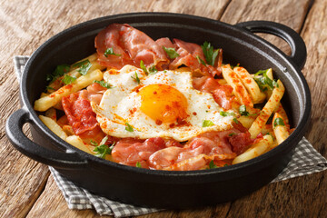 Spanish style fried egg with French fries and jamon close-up in a plate on the table. horizontal