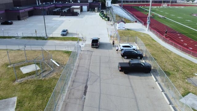 A Truck Drives Through A High School Parking Lot.