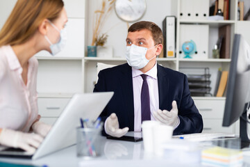 Obraz premium Office workers in protective medical masks work at the computer
