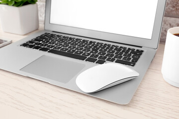 Modern laptop and wireless mouse on table