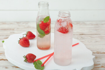 Bottles of fresh strawberry lemonade on table