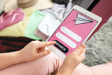 Woman with tablet computer booking tickets online at home