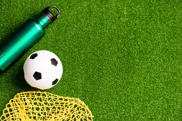 Obraz premium Soccer ball, bottle of water and net on green field