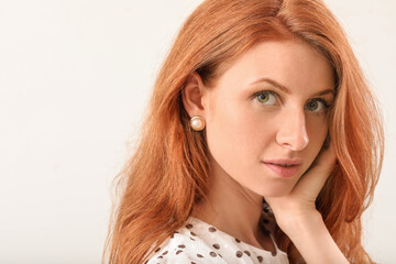 Fototapeta premium Beautiful young redhead woman on light background