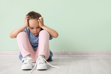 Fototapeta na wymiar Little girl with autistic disorder sitting near color wall