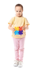 Little girl with autistic disorder and puzzle pieces on white background
