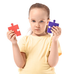 Little girl with autistic disorder and puzzle pieces on white background