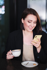 happy smiling young woman sitting at table in cafe looking cellphone - 368181061