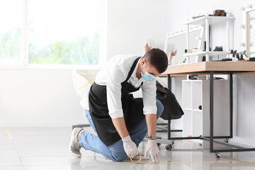 Male hairdresser applying a marking tape on floor in salon during coronavirus epidemic