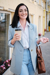 smiling businesswoman holding cofee in urban background - 368181890
