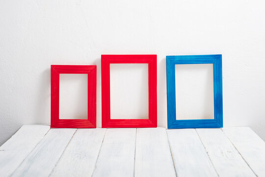 empty red and blue picture frames on white wooden table