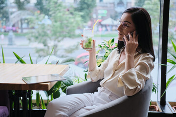 smiling businesswoman talking cellphone in city cafe - 368183014