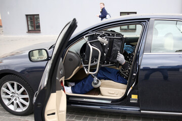 Fototapeta premium driver with disability, a disabled person loads a wheelchair into his car