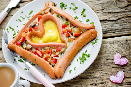 Valentine's day breakfast or brunch - fried eggs with sausage and vegetables in the shape of heart , romantic food for lovers
