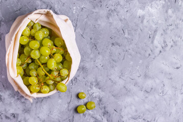 Grapes in a reusable eco cotton bag on a gray background