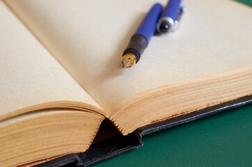 The fountain pen is lying on the open book. Close up