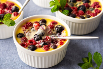 Delicious clafoutis made from white yogurt and berries, raspberries and blueberries, clafoutis in portioned bowls on the table