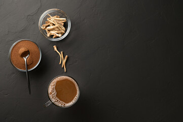 Alternative to coffee. Healthy drink chicory. Chicory coffee in a cup, roots and powder in bowls on a black background. Top view, space for text.
