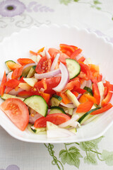 Vegetarian food. Salad of tomatoes, cucumbers, sweet peppers and onions drizzled with vegetable oil. Salad in a white plate.