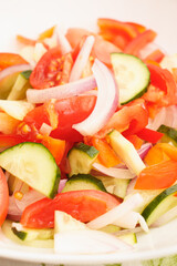 Vegetarian food. Salad of tomatoes, cucumbers, sweet peppers and onions drizzled with vegetable oil. Salad in a white plate.
