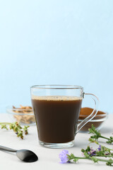 Alternative to coffee. Healthy drink chicory. Chicory coffee in a glass cup on a light gray table. Copy space, vertical orientation.