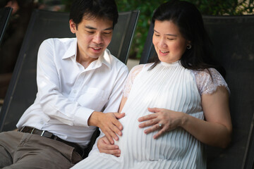 An Asian middle-aged man is proud of his first child and his wife. Touching, interacting with children, feelings, responses