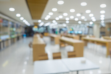Blur of white table and wooden table on food court in shopping mall.