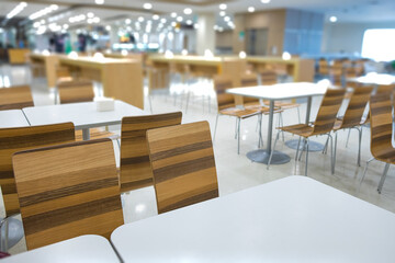 Interior of white table and wooden table on food court in shopping mall.