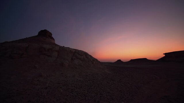 Panning camera shot of Zekreet desert in Qatar during dusk with hills in the foreground.
