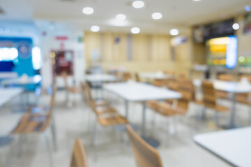 Blur of white table and wooden table on food court in shopping mall.