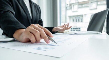 The hands of a male businesswoman are analyzing and calculating the annual income and expenses in a financial graph that shows results To summarize balances overall in office