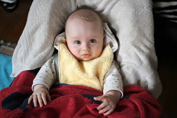 newborn baby boy with bib in the seat, eating