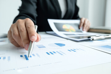 The hands of a male businesswoman are analyzing and calculating the annual income and expenses in a financial graph that shows results To summarize balances overall in office