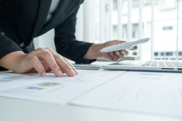 The hands of a male businesswoman use the calculator are analyzing and calculating the annual income and expenses in a financial graph that shows results To summarize balances overall in office