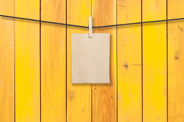 clothespin hanging with blank paper on wooden background
