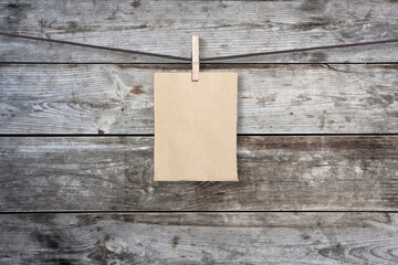 clothespin hanging with blank paper on wooden background
