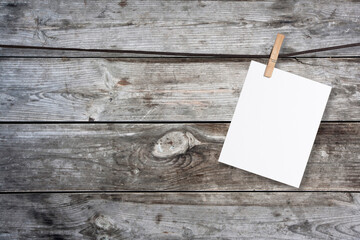 clothespin hanging with blank paper on wooden background
