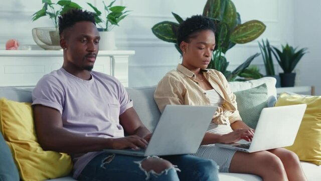 Young business african american couple using laptops performing job tasks working togeyher from home. Distant work. House apartment interior.
