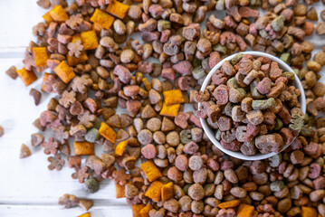 Top view of colorful dry pet food in a white ceramic bowl